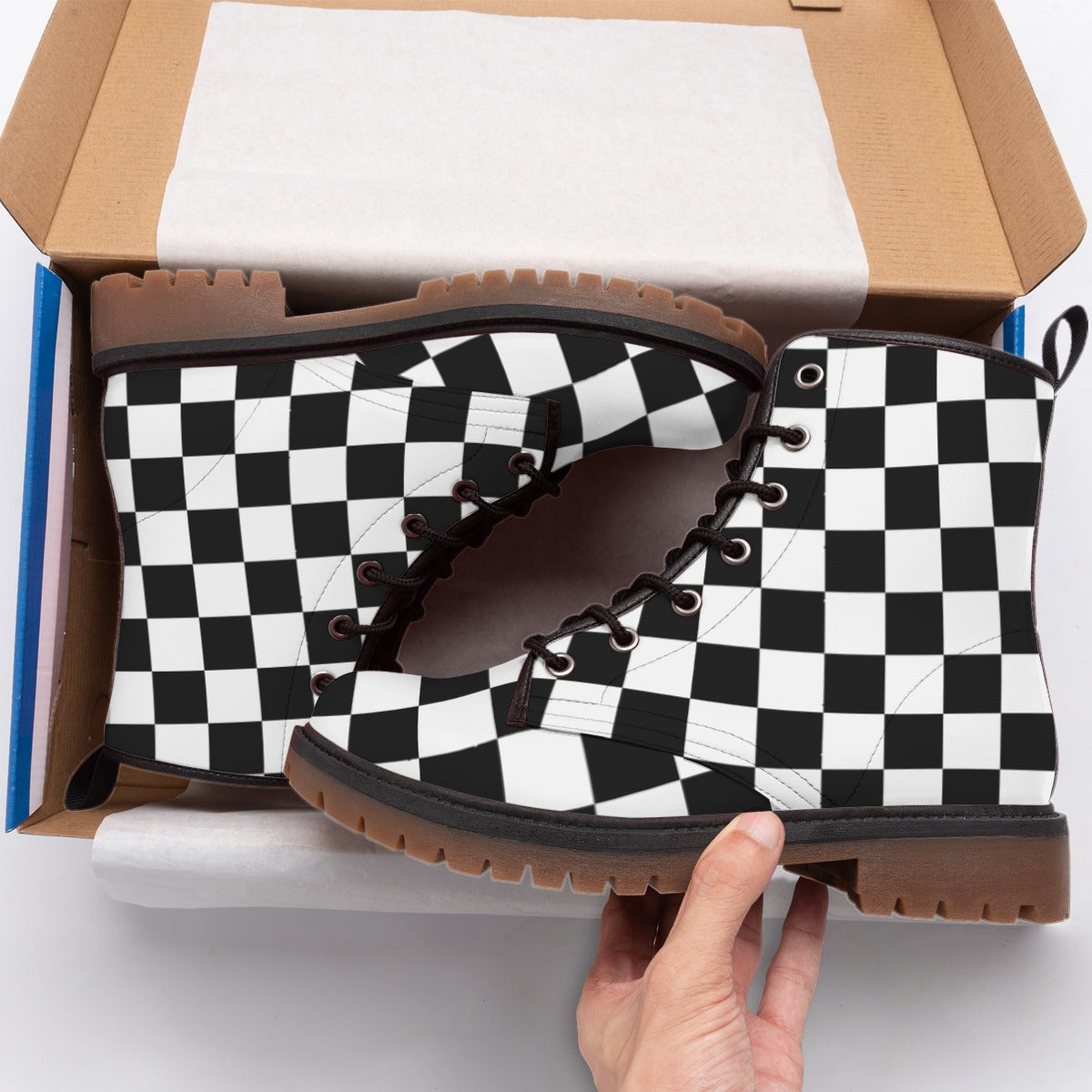 Black and white checkered boots being held above an open shoe box