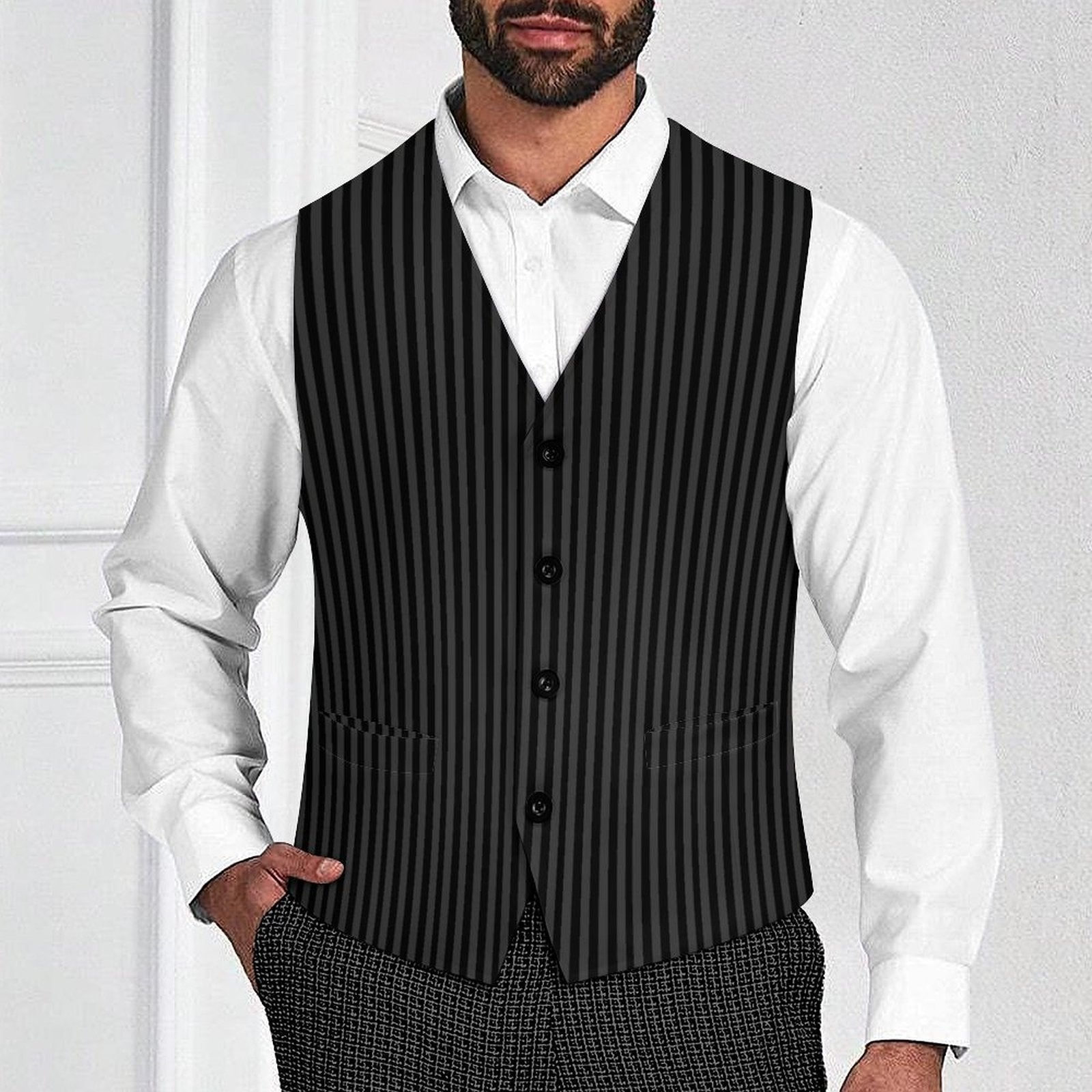 Man wearing a black pinstripe vest over a white shirt with a plain background