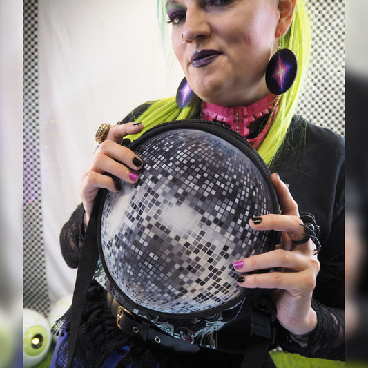 Person holding a disco ball purse with a colorful background