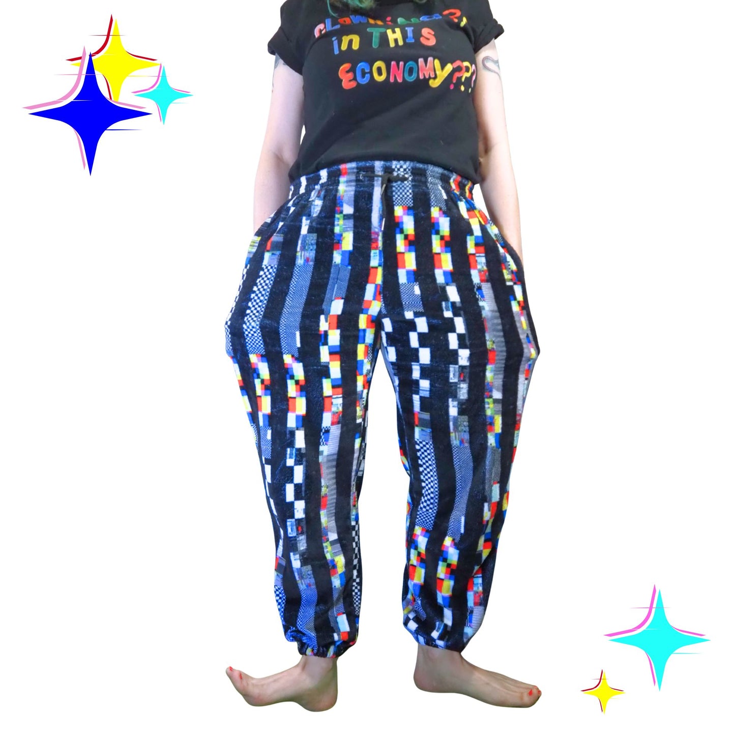 Person wearing colorful patterned pants and a black t-shirt with text on a white background