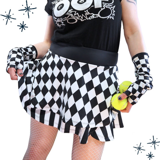 Person wearing a black and white checkered skirt with matching gloves and a black t-shirt with white graphics.