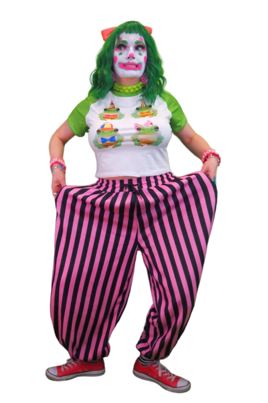 Person in colorful outfit with striped pants and green hair against a green curtain background