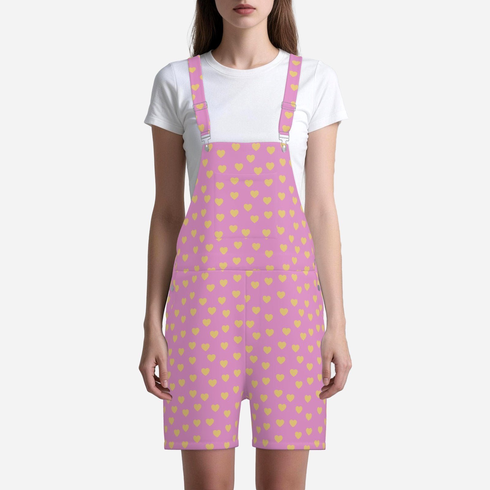 Person wearing pink overall shorts with yellow heart pattern on a white background
