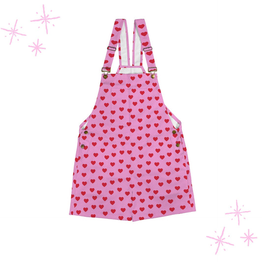 Pink shortie overalls with red heart pattern and suspenders on a white background