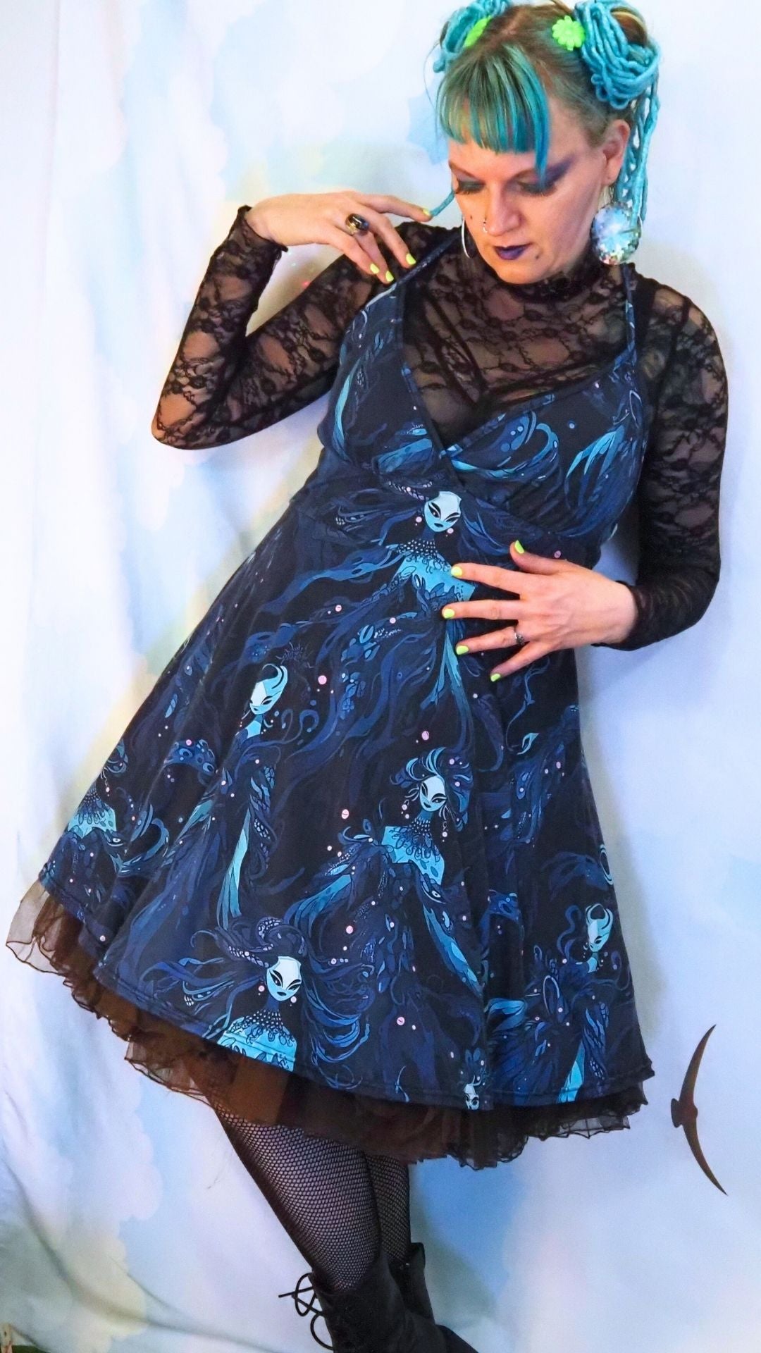 Person wearing a black dress with blue sea witch patterns against a white background