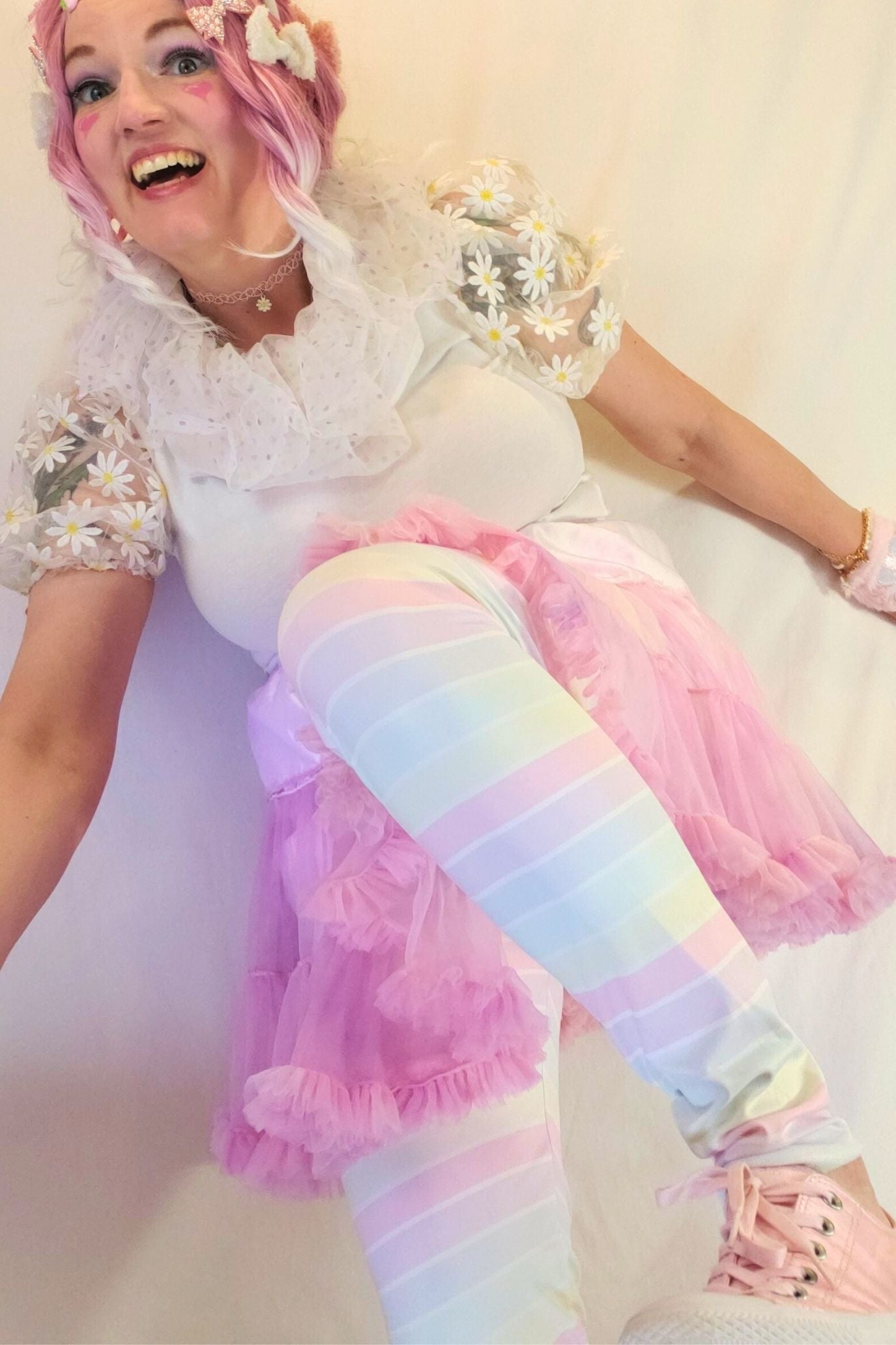 Person wearing a colorful outfit with pastel hues on a plain background
