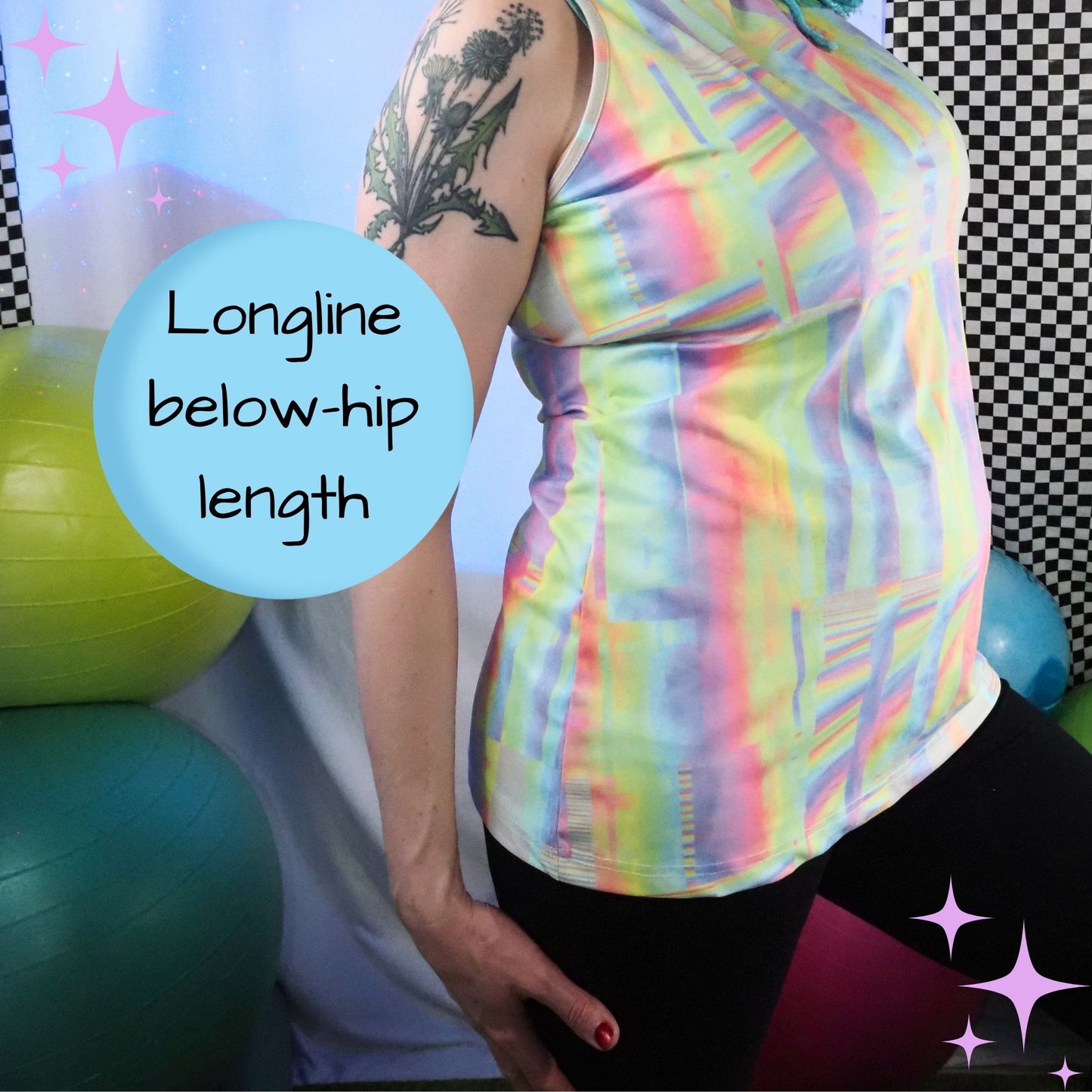 A woman wearing a longline, below-hip-length athletic tank top with a pastel rainbow irregular stripe pattern. The image features a light blue circular text overlay that reads 'Longline below-hip length' and is set against a gym background with exercise balls.