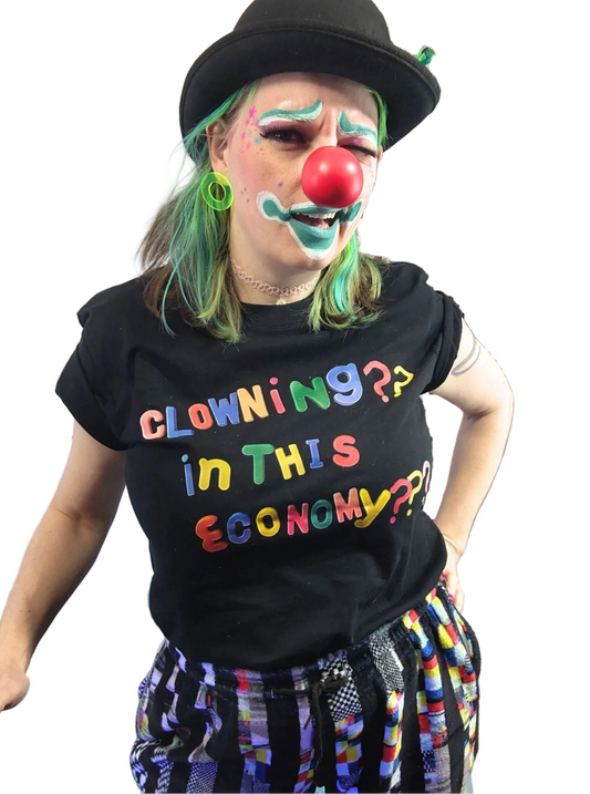 Person dressed as a clown with colorful text on a black t-shirt, surrounded by decorative elements.