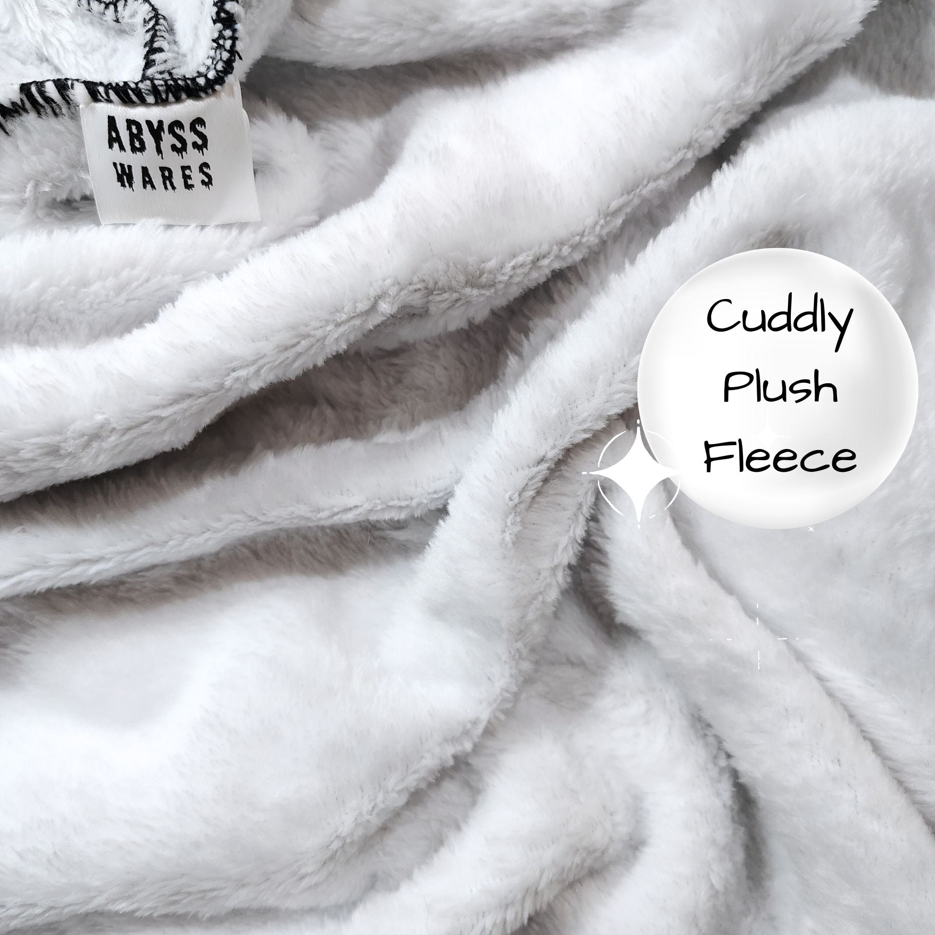Close-up of a fluffy white fabric with 'ABYSS WARES' label and 'Cuddly Plush Fleece' text.